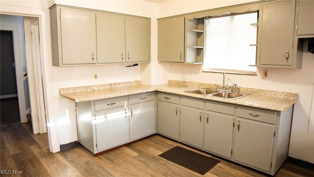 kitchen with a sink, gray cabinetry, light countertops, light wood-style flooring, and open shelves