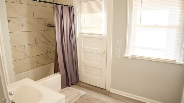 bathroom featuring baseboards, shower / bath combo with shower curtain, and wood finished floors