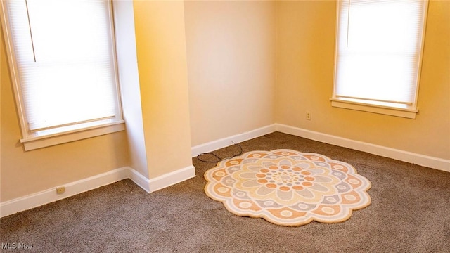 empty room with plenty of natural light, baseboards, and carpet floors