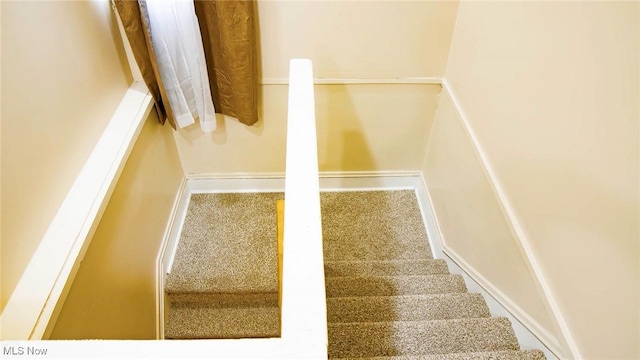 staircase featuring baseboards and carpet