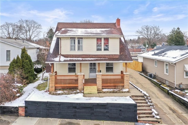 view of front facade with central air condition unit, driveway, roof with shingles, covered porch, and a chimney