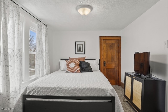 bedroom with dark colored carpet and a textured ceiling