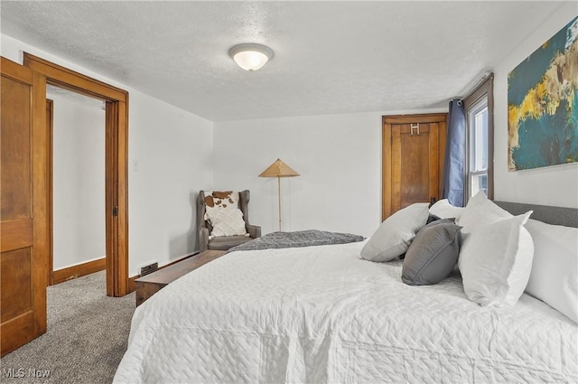 carpeted bedroom with visible vents, a textured ceiling, and baseboards