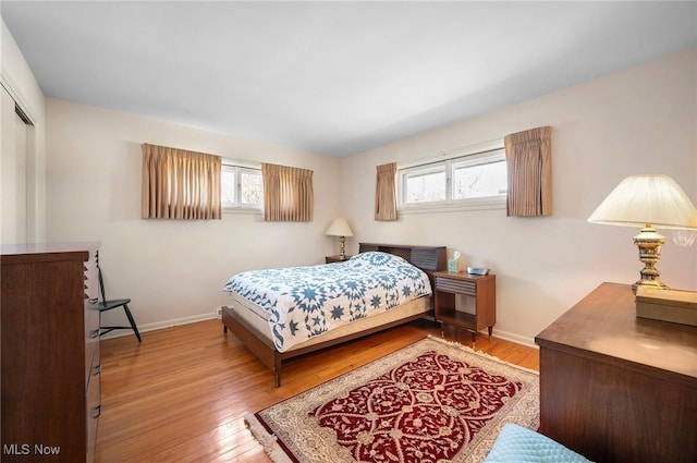 bedroom with baseboards, multiple windows, and wood finished floors