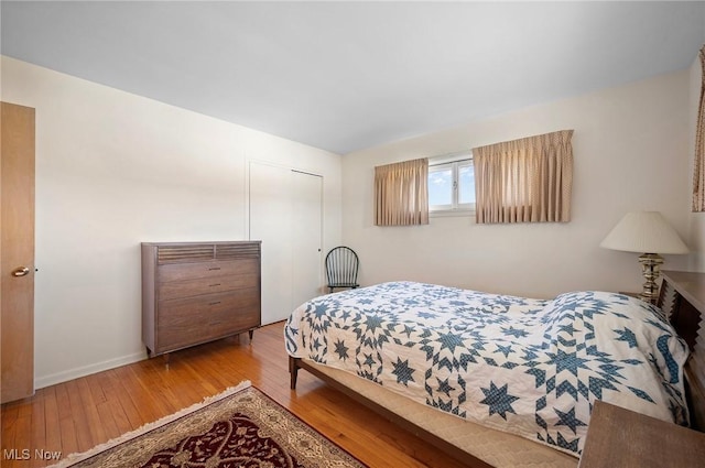 bedroom featuring wood finished floors, a closet, and baseboards