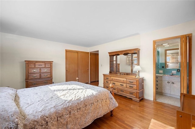 bedroom with light wood-type flooring, a closet, and ensuite bathroom