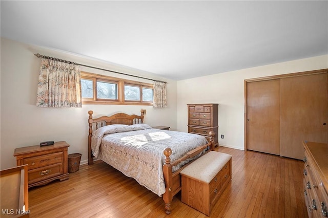 bedroom featuring light wood-type flooring, baseboards, and a closet