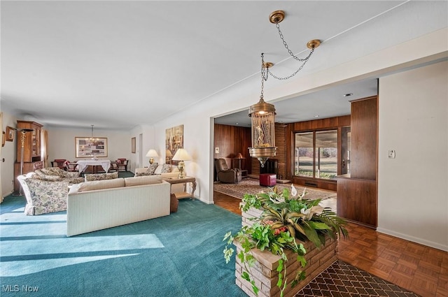 living room featuring a notable chandelier, wood walls, and baseboards