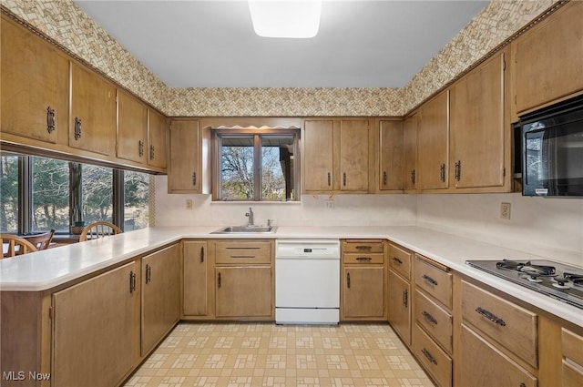 kitchen featuring a peninsula, a sink, light countertops, black microwave, and dishwasher