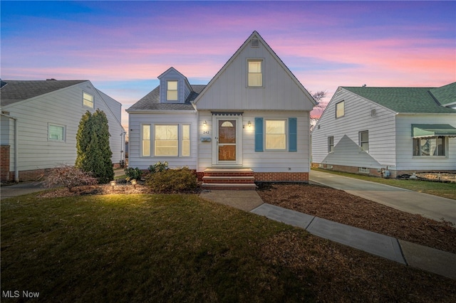 bungalow with a shingled roof and a yard