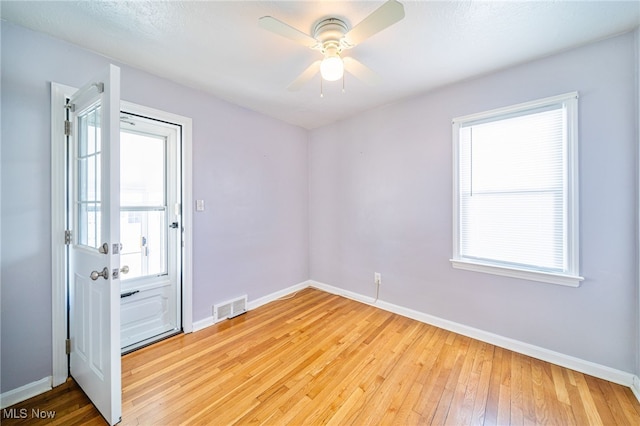 spare room with visible vents, baseboards, ceiling fan, and light wood-style flooring