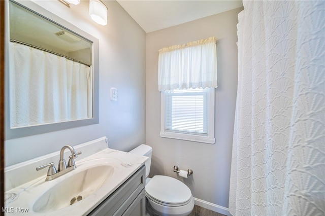 full bath with toilet, vanity, and baseboards