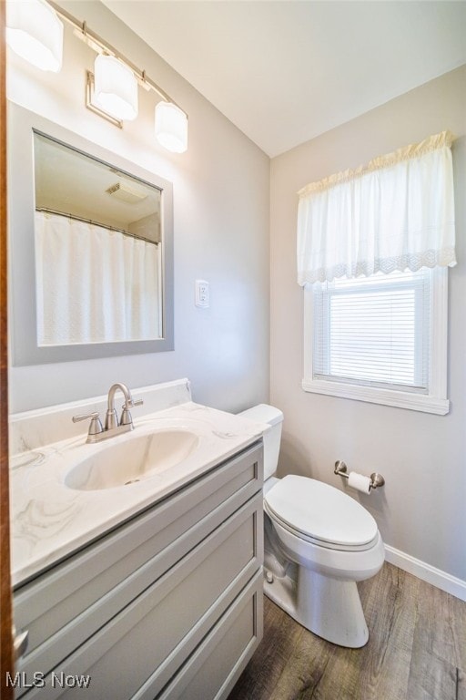 full bath with toilet, vanity, baseboards, and wood finished floors