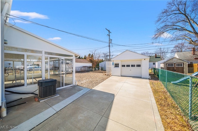 view of yard featuring a garage, an outbuilding, concrete driveway, and fence