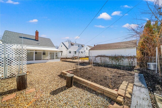 view of yard with a vegetable garden, fence, and a sunroom