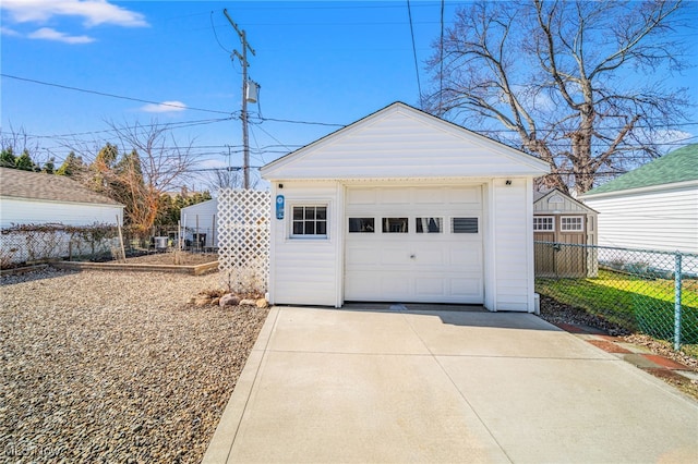 detached garage with concrete driveway and fence