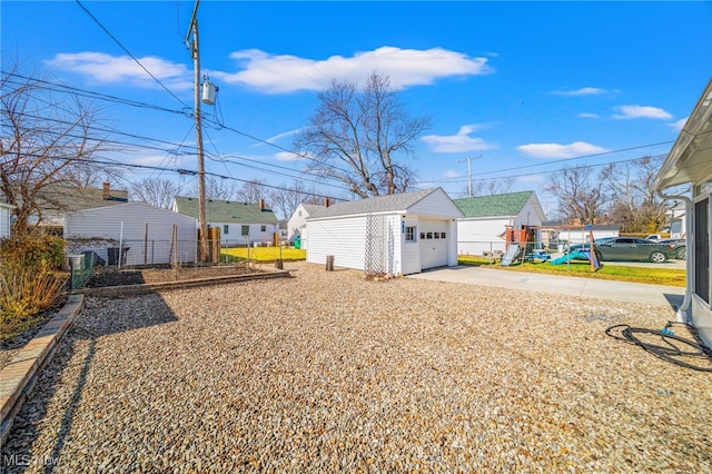 view of yard featuring a detached garage, an outdoor structure, driveway, and fence