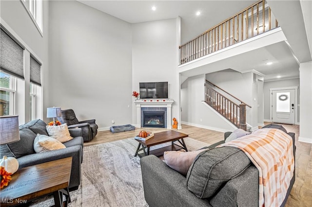 living area with wood finished floors, a towering ceiling, and stairs