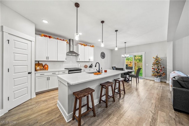 kitchen featuring electric range, light wood-style flooring, a sink, wall chimney exhaust hood, and white cabinets