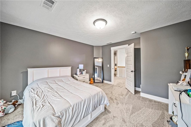 bedroom with a textured ceiling, light colored carpet, visible vents, and baseboards