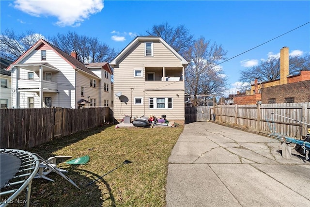 back of house with a yard, a patio area, a fenced backyard, and a balcony