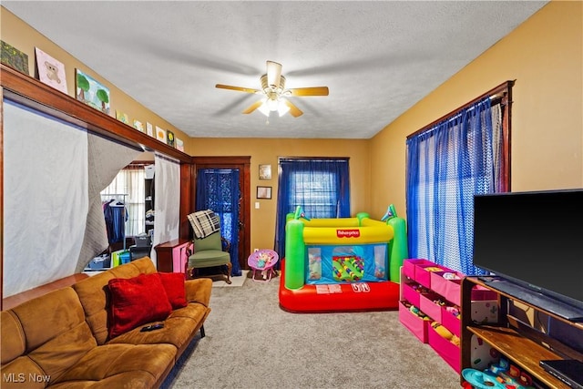 game room with a textured ceiling, carpet, and a ceiling fan