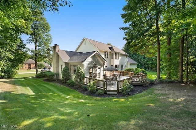 exterior space featuring a deck, a chimney, and a yard