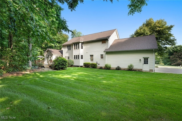 rear view of property with a lawn and a wooden deck