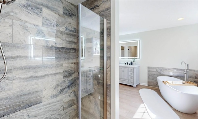 bathroom with wood finished floors, a soaking tub, a stall shower, and vanity