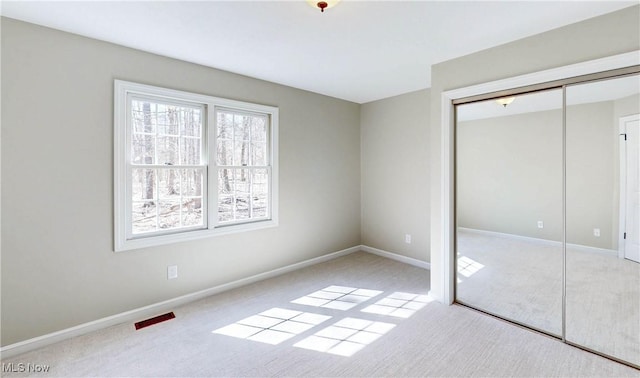 unfurnished bedroom featuring a closet, carpet flooring, visible vents, and baseboards