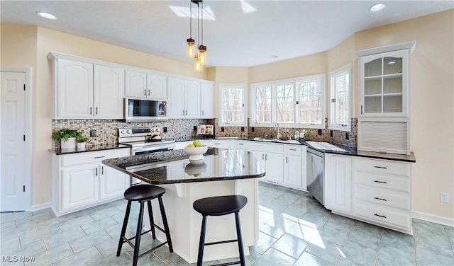 kitchen featuring a sink, a kitchen breakfast bar, a center island, white cabinetry, and stainless steel appliances