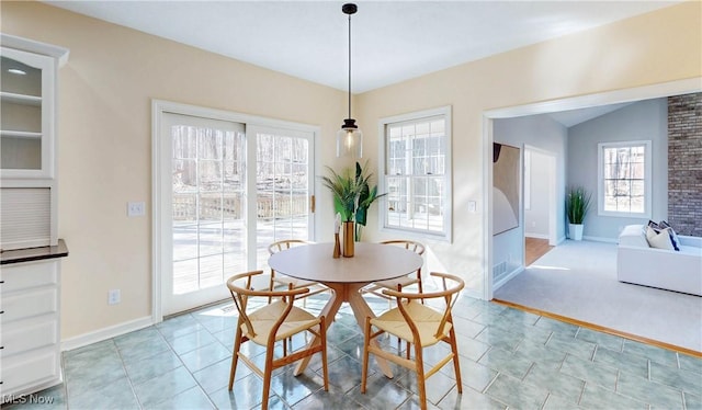 dining area with baseboards, light tile patterned flooring, and vaulted ceiling