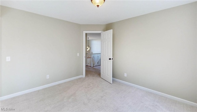 spare room featuring baseboards and light carpet