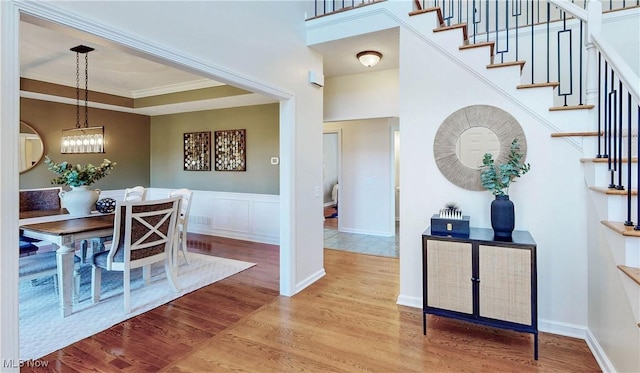 dining area with ornamental molding, wood finished floors, stairway, wainscoting, and a towering ceiling