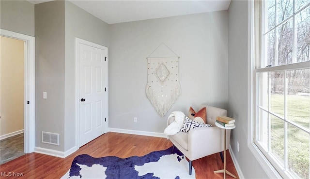 living area with wood finished floors, visible vents, and baseboards