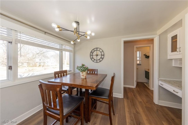 dining room with a notable chandelier, baseboards, and dark wood-style flooring