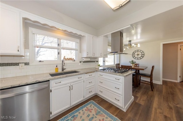 kitchen featuring a peninsula, a sink, stainless steel appliances, white cabinetry, and island range hood