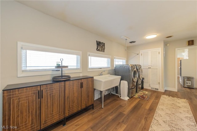 laundry area with wood finished floors, baseboards, visible vents, laundry area, and washing machine and dryer