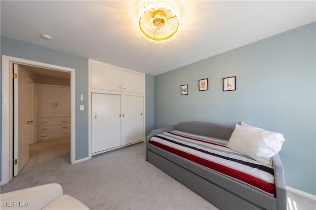 bedroom featuring light colored carpet, a closet, and baseboards