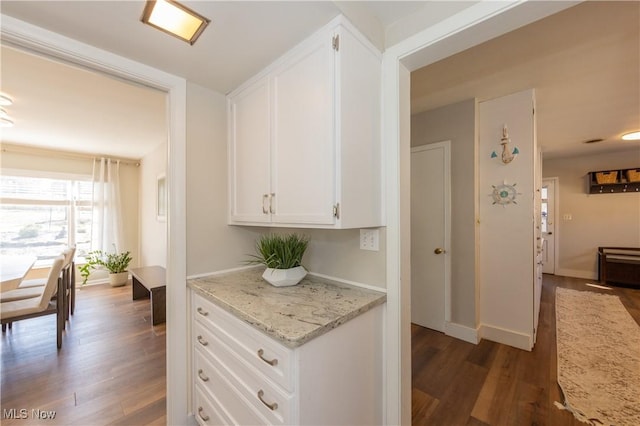 kitchen with white cabinets, light stone countertops, baseboards, and wood finished floors