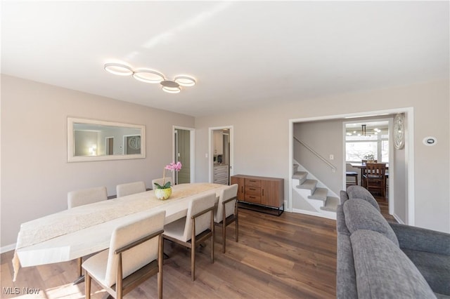 dining space with baseboards, an inviting chandelier, dark wood-style floors, and stairs