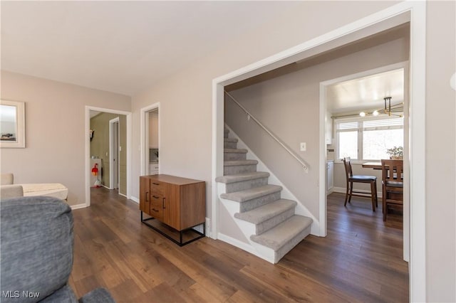 interior space featuring a notable chandelier, baseboards, stairs, and dark wood-type flooring