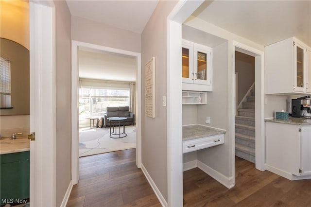 corridor featuring dark wood-style floors, stairs, and baseboards