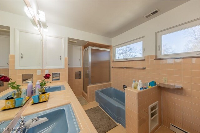 full bath featuring visible vents, a shower stall, a baseboard heating unit, a garden tub, and tile walls