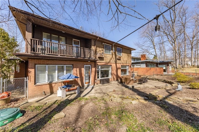 back of property with a patio, a balcony, brick siding, and fence