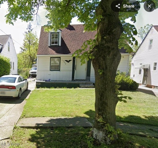 cape cod-style house with roof with shingles and a front lawn