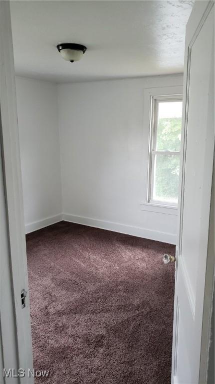 unfurnished room with baseboards and carpet