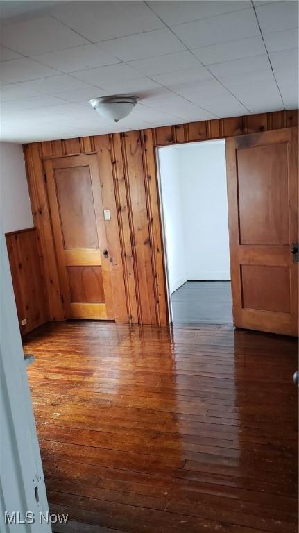 spare room with dark wood-style flooring and wood walls