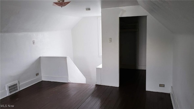 additional living space featuring hardwood / wood-style floors, vaulted ceiling, baseboards, and visible vents