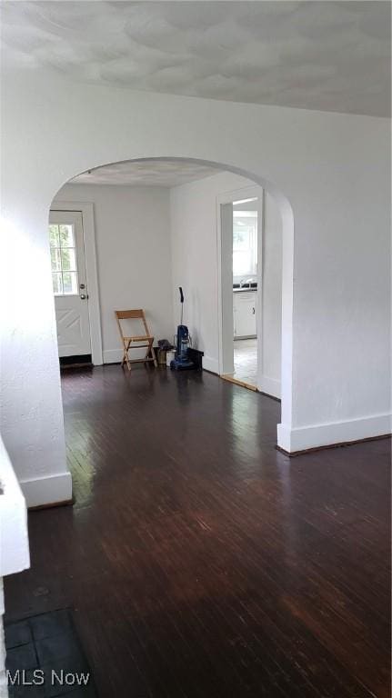 interior space featuring baseboards, arched walkways, and wood finished floors